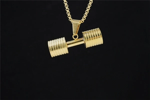 Macro shot of golden dumbbell pendant and box chain against a black background