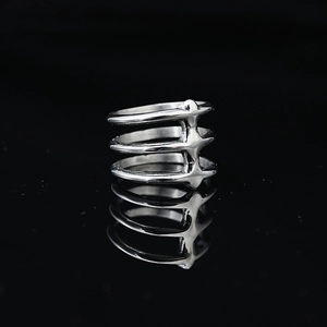 Minimalist silver triple-layered spine ring with punk spiked accents on black surface