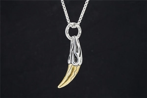 Detailed view of two-tone wolf tooth pendant with silver flame textures and gold tip