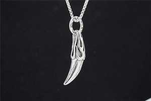 Detail of silver stainless steel wolf tooth pendant with flame carvings and box chain
