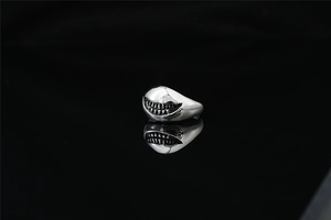 Détail macro de la bague sourire de requin en acier argenté avec gravure de style punk