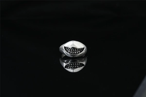Détail d'une bague punk argentée en forme de gueule de requin avec design de dents de monstre