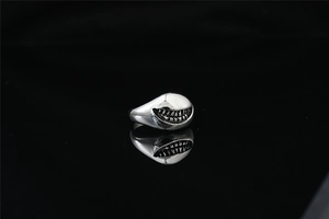 Gros plan d'une bague sourire de requin gothique avec relief argenté et reflet miroir