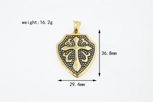 Detailed close-up of golden shield pendant with cross relief and dotted texture