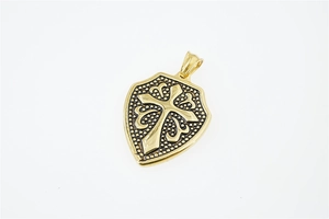 Macro shot of gold shield pendant featuring a relief cross and caviar texture