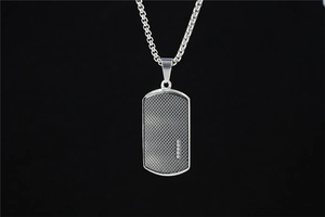 Gros plan détaillé d'un pendentif plaque argenté avec texture grillagée et quatre zircons