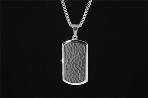 Détail d'un collier plaque militaire en acier titane avec texture martelée et diamants