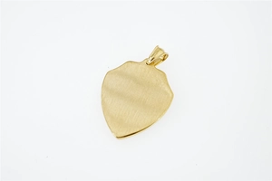 Detail of golden shield pendant with brushed metal finish on white background