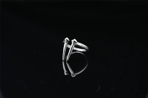 Detalle macro de un anillo de acero de titanio plateado con doble punta en superficie reflectante