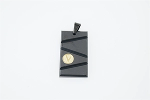 Détail d'un pendentif rectangulaire noir mat avec emblème V doré et rainures diagonales