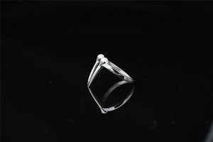 Anillo de acero de titanio pulido con dos puntas de cuerno sobre fondo negro liso