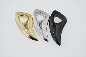 Detail of wolf tooth pendants in gold, silver, and black with a high-gloss metallic finish