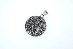 Macro d'un pendentif Vierge Marie en métal argenté avec gravure de prière et détails relief