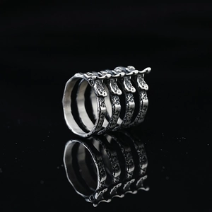 Punk style rib-shaped spinal ring in retro blackened titanium steel on black background