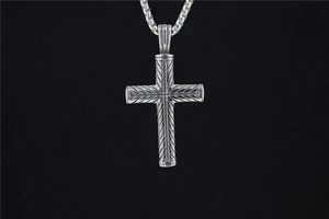 Vue macro du pendentif croix hip-hop en argent avec motifs sculptés sur fond noir profond