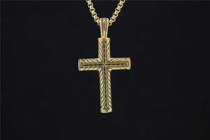 Vue détaillée du pendentif croix dorée hip-hop avec des motifs de plumes gravés