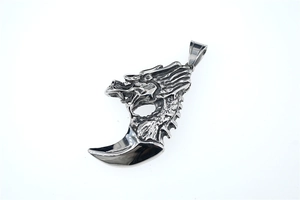 Macro detail of gothic wolf tooth pendant with dragon head in polished steel