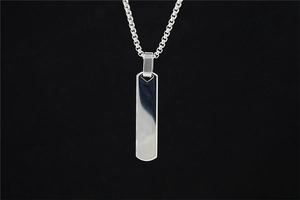 Macro detail of polished stainless steel rectangular bar pendant on a box chain