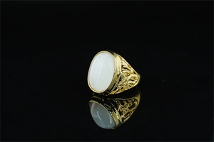 Detail shot of a golden men's dragon ring with large white oval opal gemstone and hollow patterns
