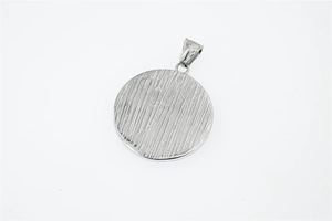 Detail of round viking bear paw pendant with vertical brushed texture in steel