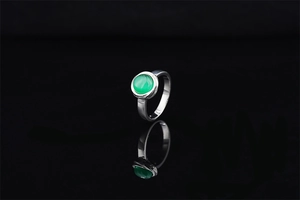 Detail view of a minimalist silver ring with a polished green gemstone on a black reflection