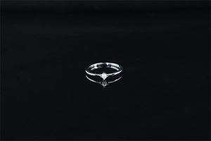 Vue détaillée d'une bague fine en argent avec perle et serti à quatre griffes sur fond noir