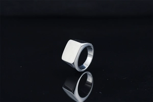 Macro shot of silver minimalist square signet ring for men on a black reflective surface