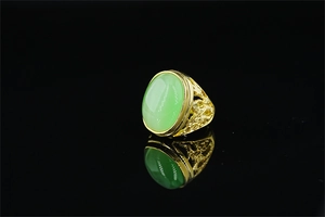 Detailed relief of a golden dragon on the ring shank with a green gemstone center