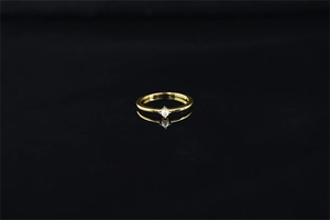 Vue détaillée d'une bague dorée minimaliste avec une perle blanche sur surface noire