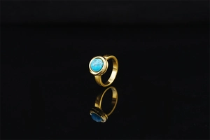 Close-up of golden ring featuring a round turquoise gemstone with natural vein patterns
