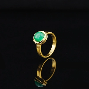 Elegant minimalist gold ring featuring a polished green gemstone on a dark reflective surface