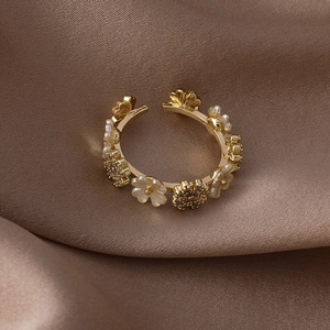 Close-up of gold shell flower ring with micro-set zircon on champagne silk background