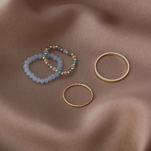 Detail of four-piece stackable ring set with blue crystal beads and golden metal bands