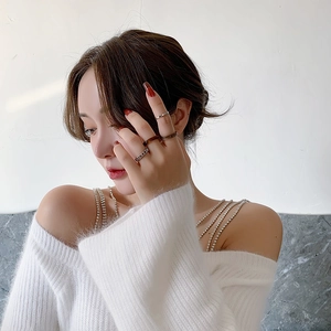 Close-up of stylish acrylic and metal ring set worn by model with elegant white sweater