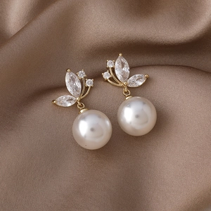Vue macro de boucles d'oreilles perles papillon dorées avec zircons sur satin brun