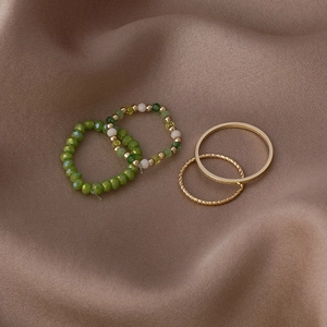 Close-up of four-piece ring set with colorful crystal beads and gold bands on brown silk