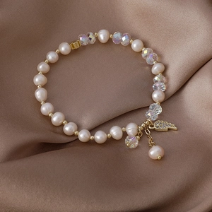 Freshwater pearl bracelet with angel wing pendant on elegant brown silk background