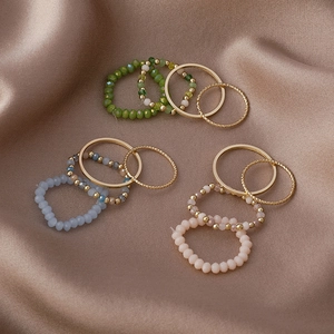 Detailed macro view of colorful crystal beaded rings and gold bands on satin fabric