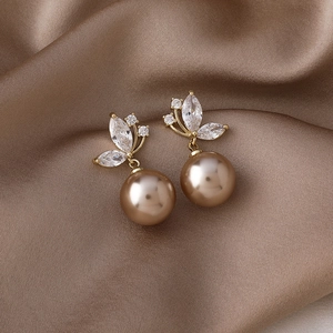 Détail de boucles d'oreilles papillon dorées avec zircon et perles marron champagne