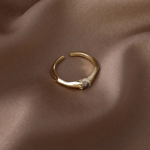Gros plan d'une bague dorée ajustable avec zircon brun sur un fond en soie brune
