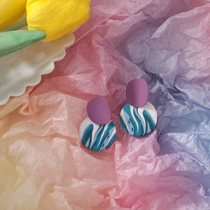 Handmade clay earrings featuring purple studs and blue abstract water pattern round pendants