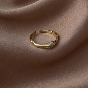 Détail d'une bague dorée avec zircon violet sur fond de soie texturée élégante