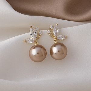 Détail de boucles d'oreilles papillon dorées avec zircone et perle de couleur champagne