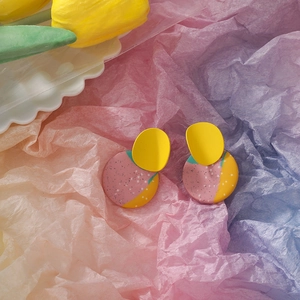Detail view of handmade clay geometric earrings with colorful splatter pattern on a tray