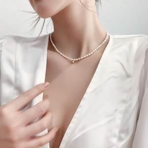 Minimalist freshwater pearl choker with a golden bead pendant on a model's neck