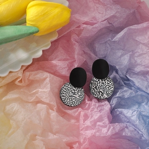 Detailed view of handmade geometric clay earrings with black and white leopard patterns