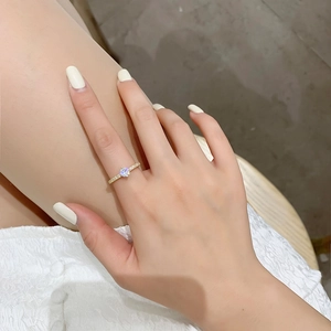 Gros plan d'une bague dorée avec zircon central rond et serti pavé sur le doigt