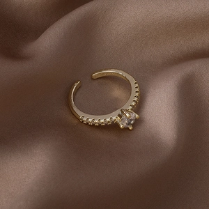 Gros plan d'une bague réglable dorée avec un zircon rond brillant et des pierres latérales