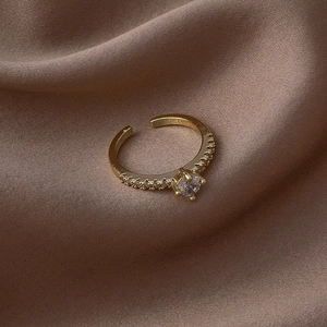 Gros plan d'une bague réglable en or avec pierre de zircon sur de la soie marron