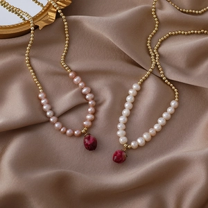 Handmade pearl necklace with preserved rose pendant on gold chain and silk backdrop